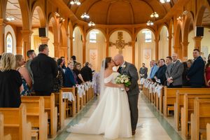 A wedding ceremony in a grand cathedral with wooden pews and ornate architecture illuminated by warm lighting.