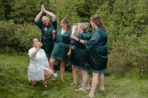 A group in green jackets poses playfully in a grassy outdoor setting during a photo session.