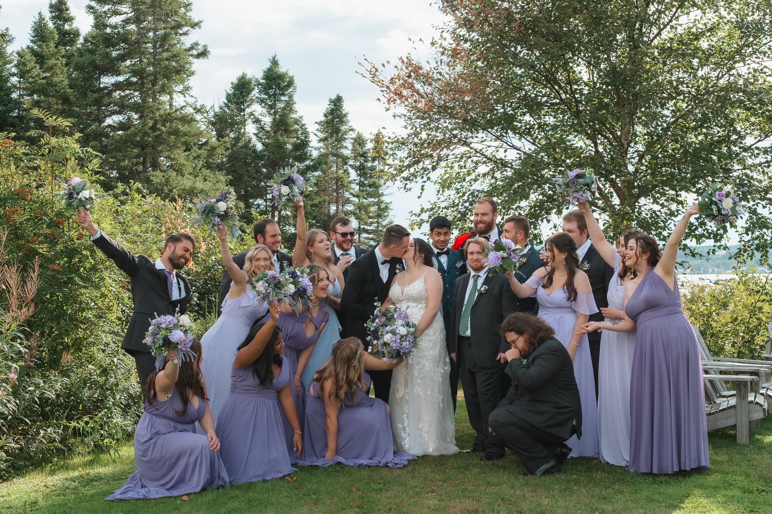 cheering wedding party with bride and groom kissing
