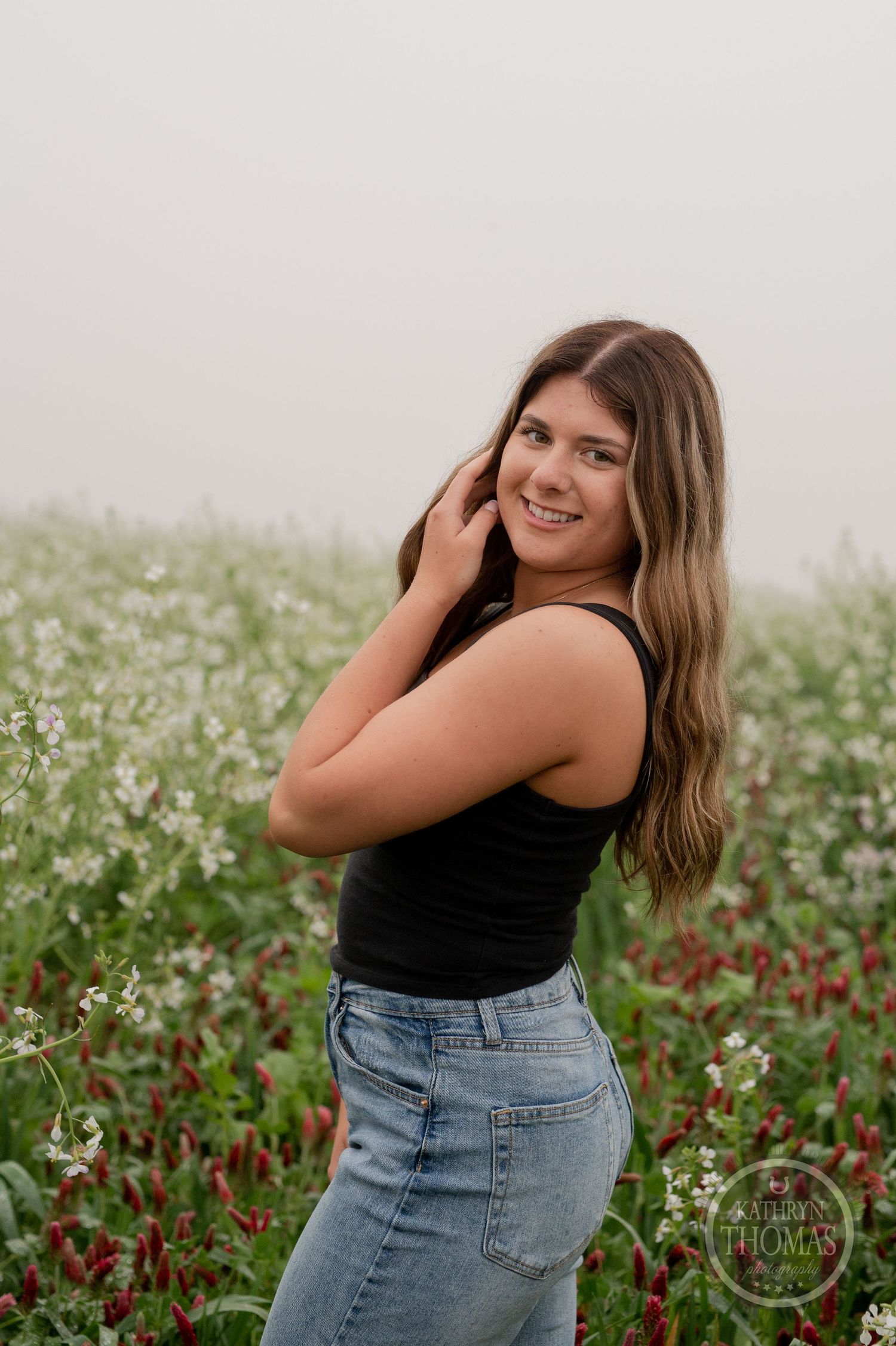 Playful portrait in a wildflower field wearing casual summer outfit with white and red blooms.