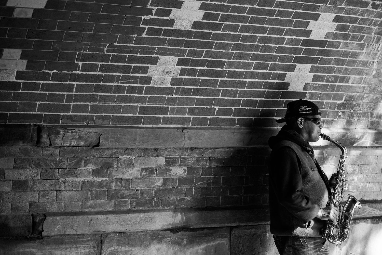 Dramatic black and white photo of shadow against brick wall with cross patterns.