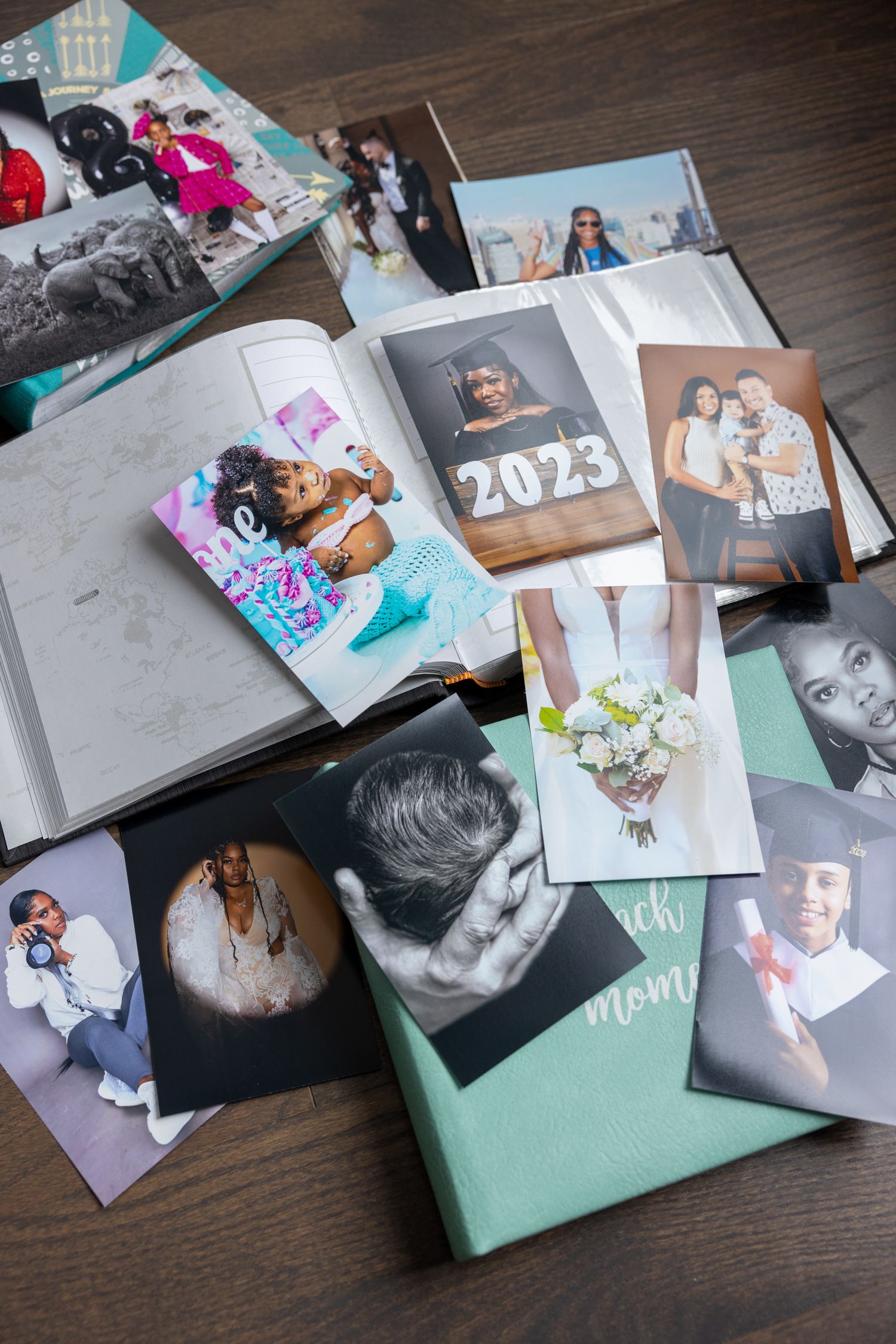 Collection of photo albums and printed photographs spread out on dark wooden surface showing personal memories and events.