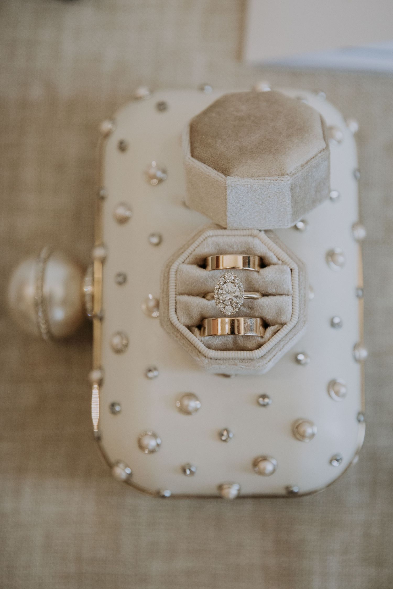 Diamond engagement ring displayed in an ornate white textured jewelry box with studded details.