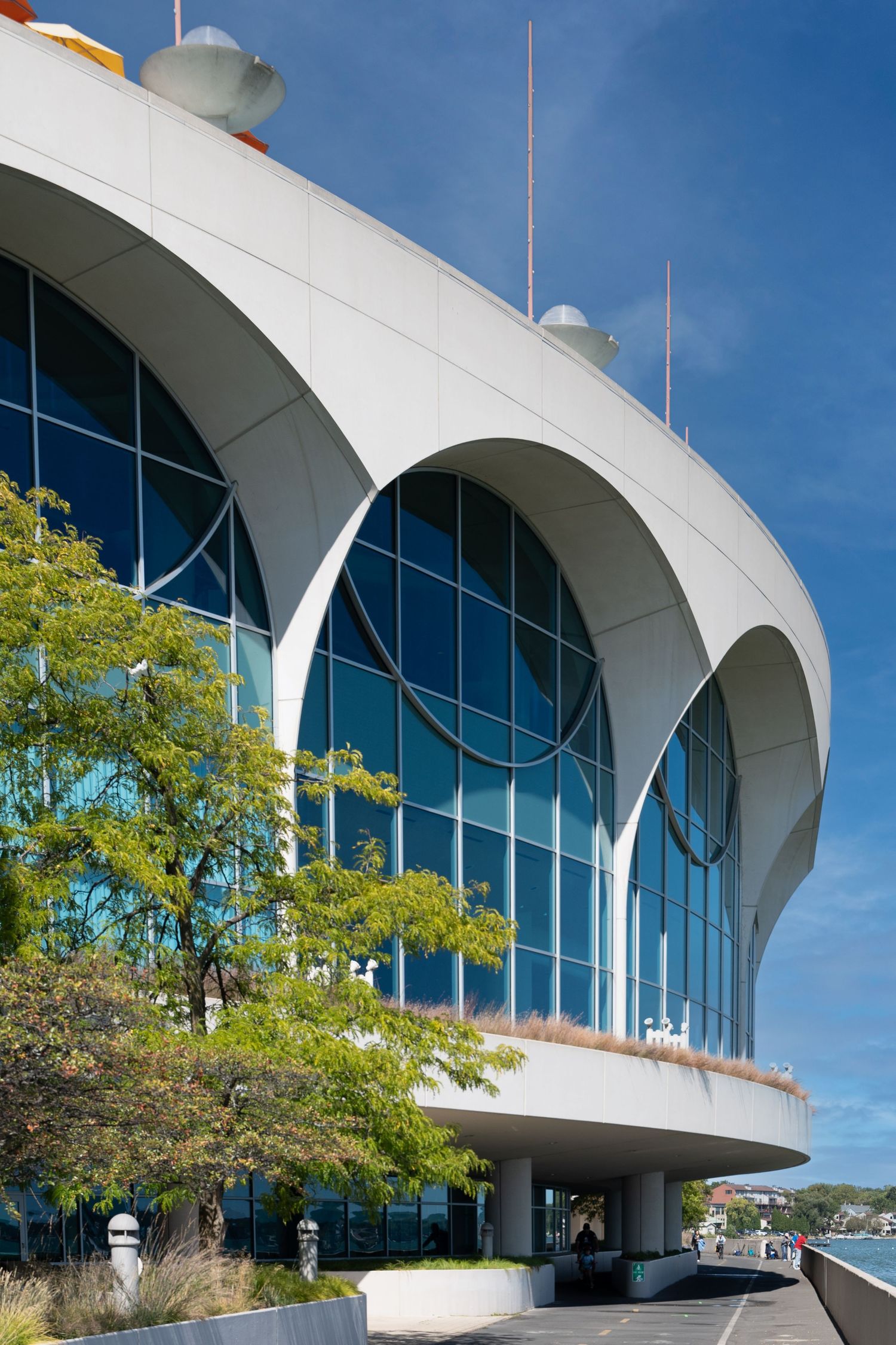 Modern curved architecture building with glass windows and white arches against blue sky.
