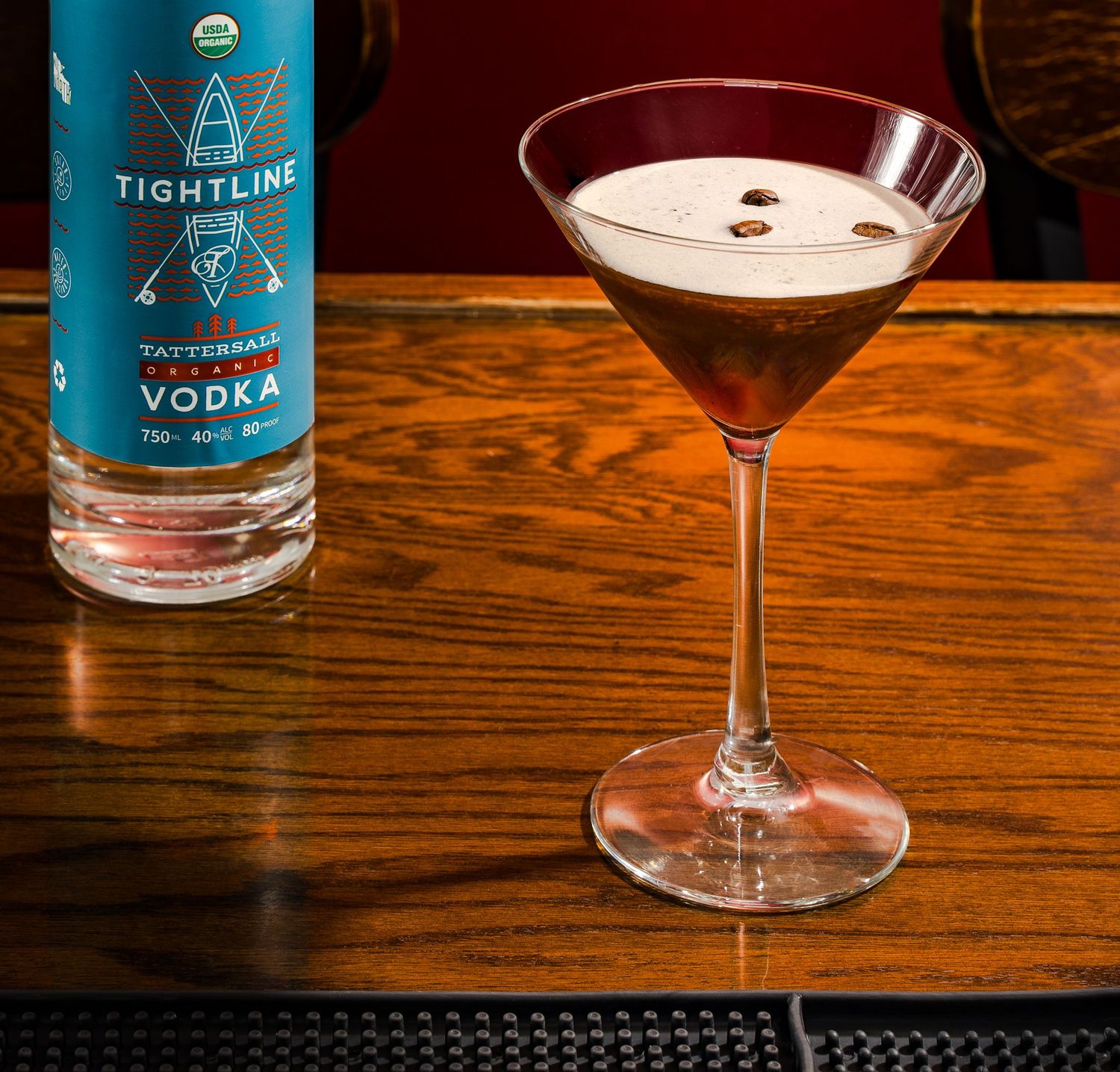 Tightline vodka bottle and martini cocktail on wooden bar top.
