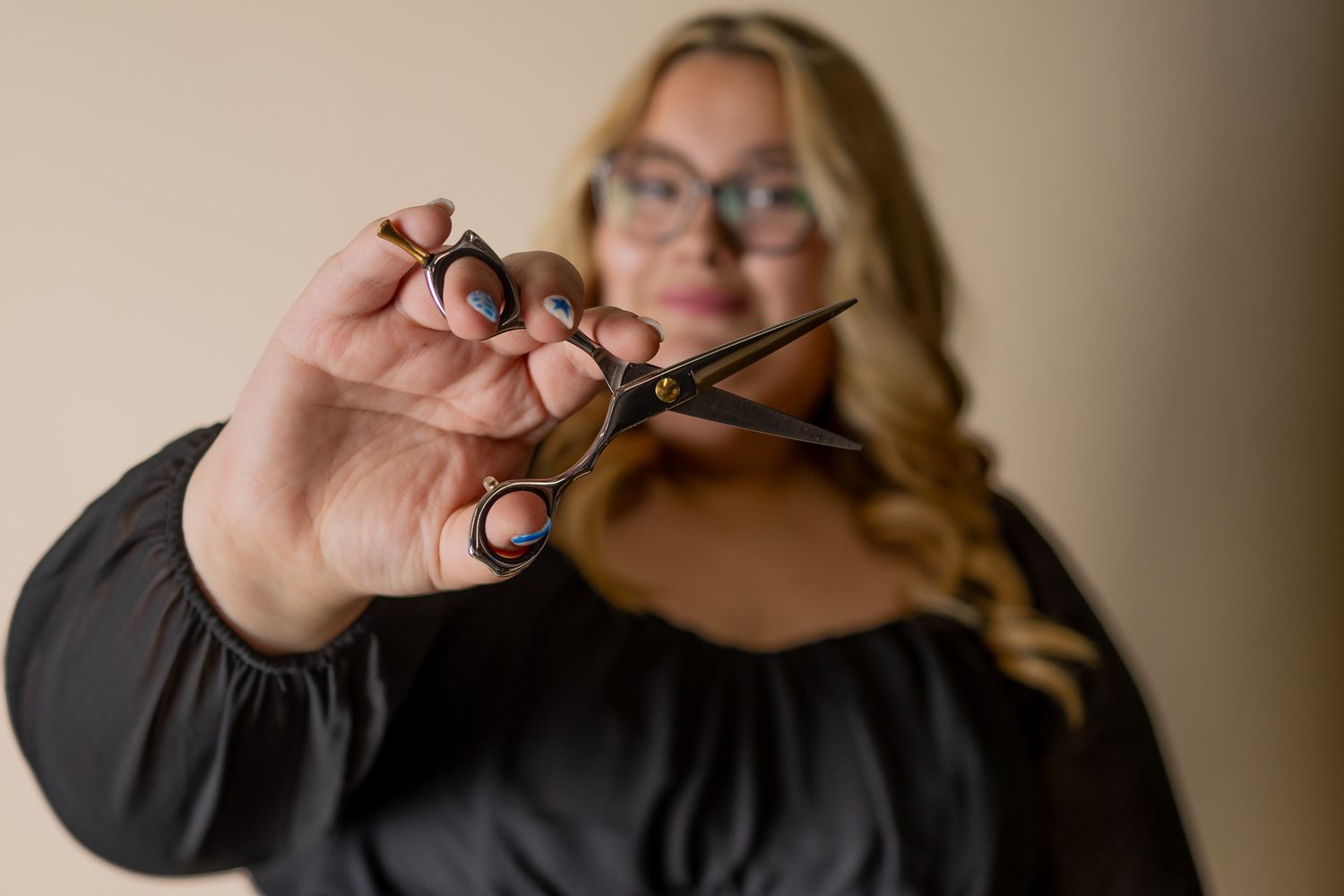 Close-up shot of hands holding professional hairdressing scissors against blurred background.