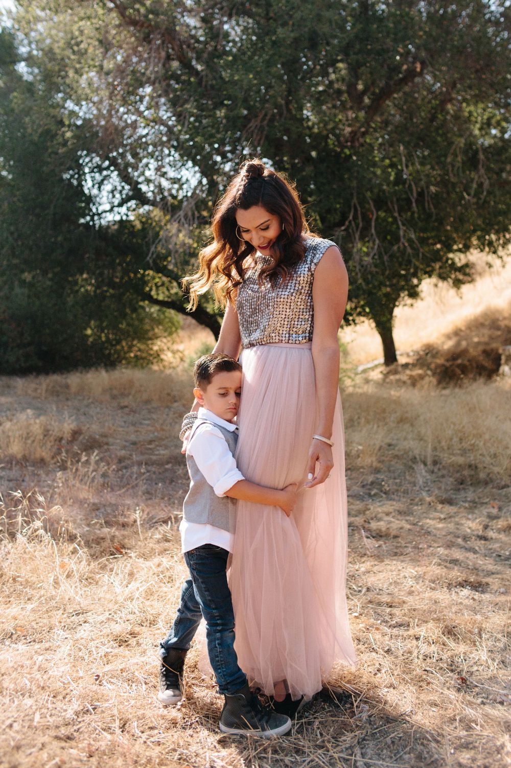 son hugging his mom, nature and trees behind them