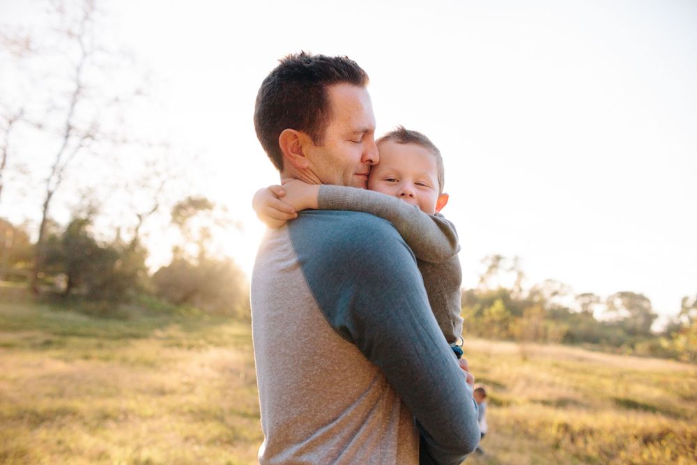 dad holding son with golden light behind them
