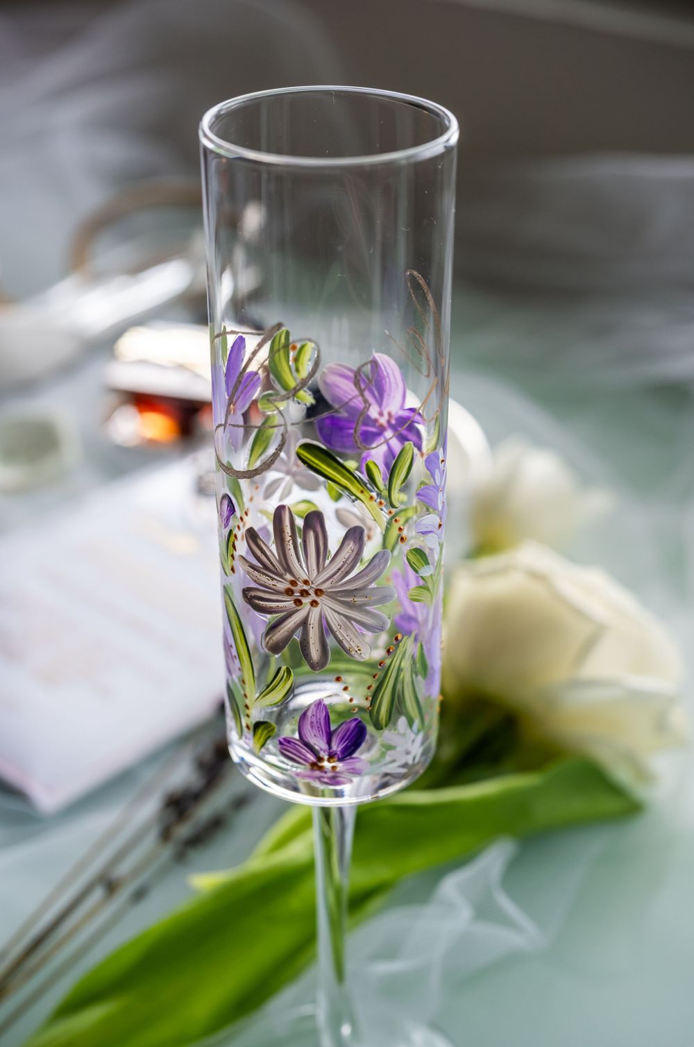Decorative champagne flute with painted purple and green floral design.