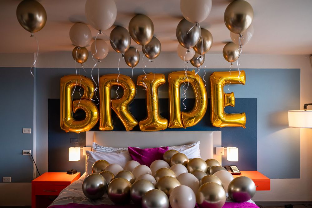 Gold 'BRIDE' balloon letters and metallic balloons decorating a bedroom for wedding preparation.