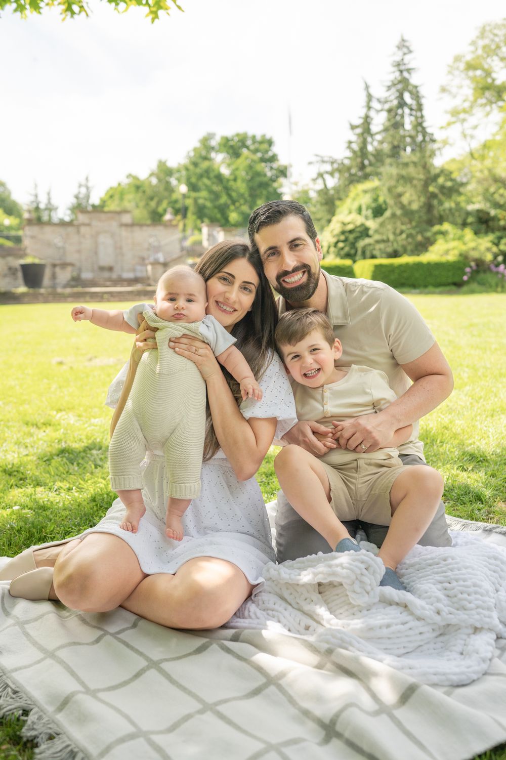 Spring Family Outdoor Park Photoshoot – A family enjoying a sunny day on a blanket in the park, capturing memories in a natural setting.