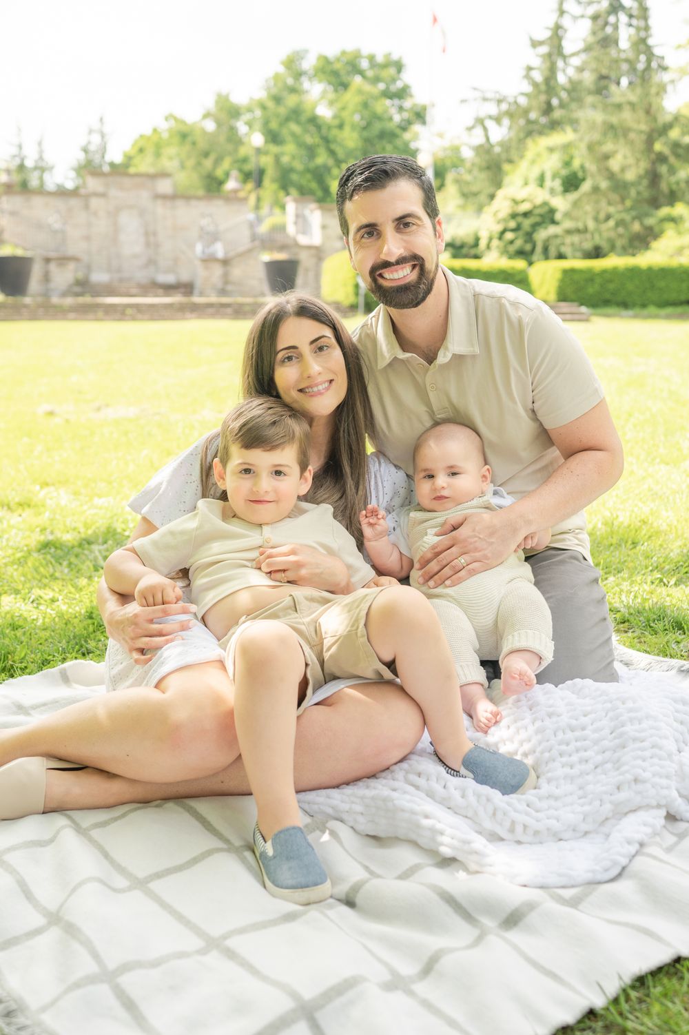 Spring Family Outdoor Park Photoshoot – A family enjoying a sunny day on a blanket in the park, capturing memories in a natural setting.