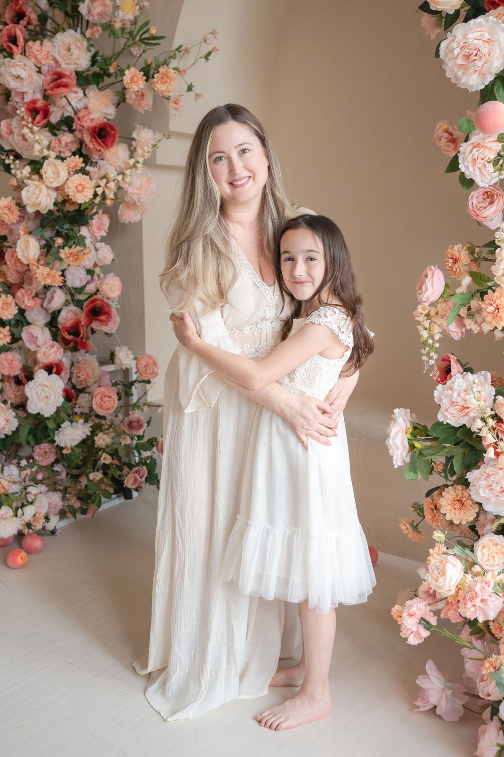Sweet embrace captured under archway decorated with lush pink and peach roses.