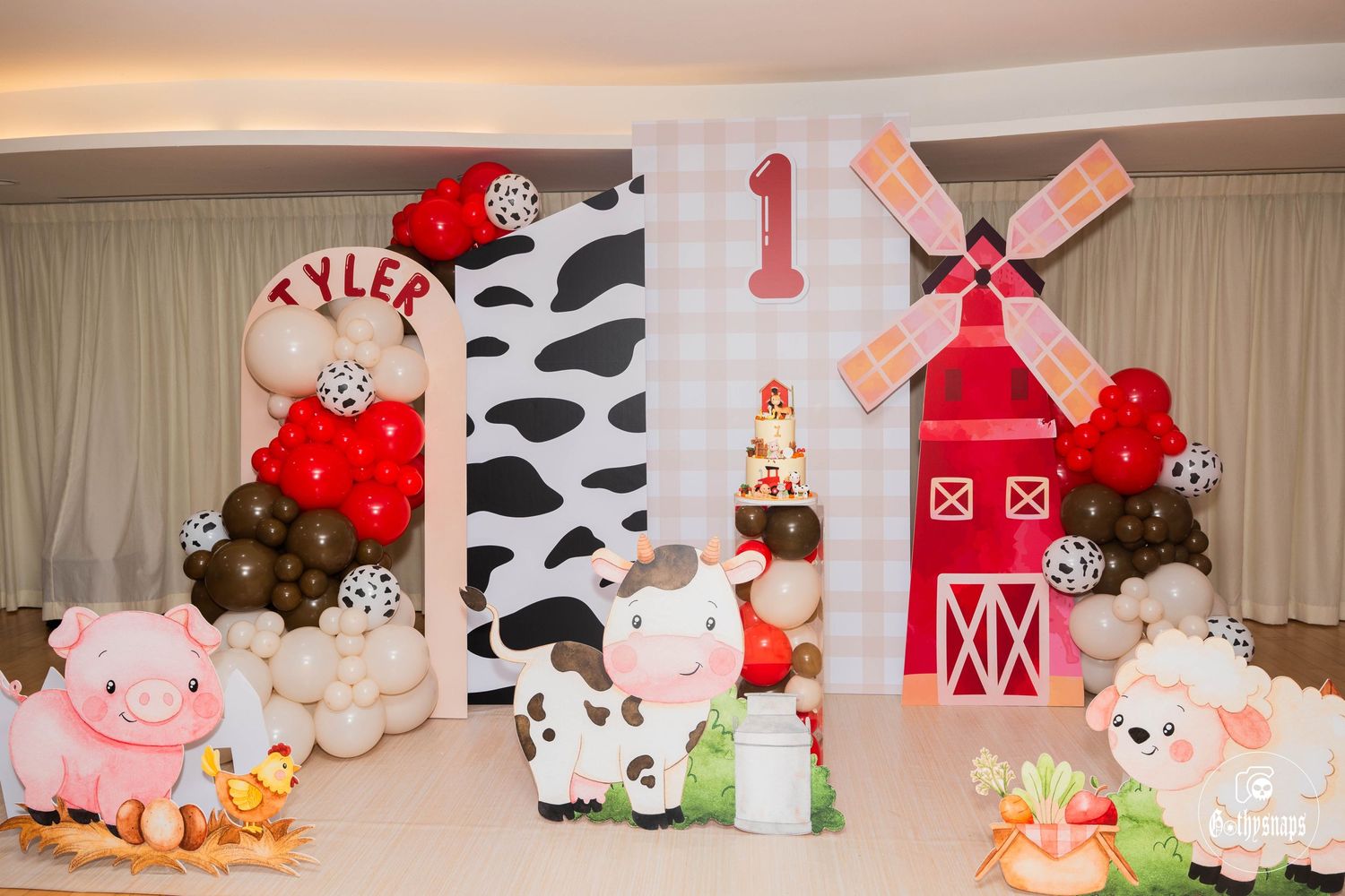 Farm themed party decoration with red barn, windmill, and cow print patterns.
