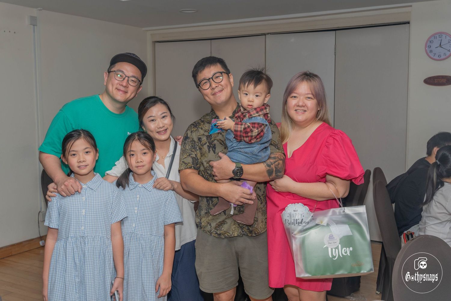 Family gathering with matching outfits in front of a white backdrop at a celebration.