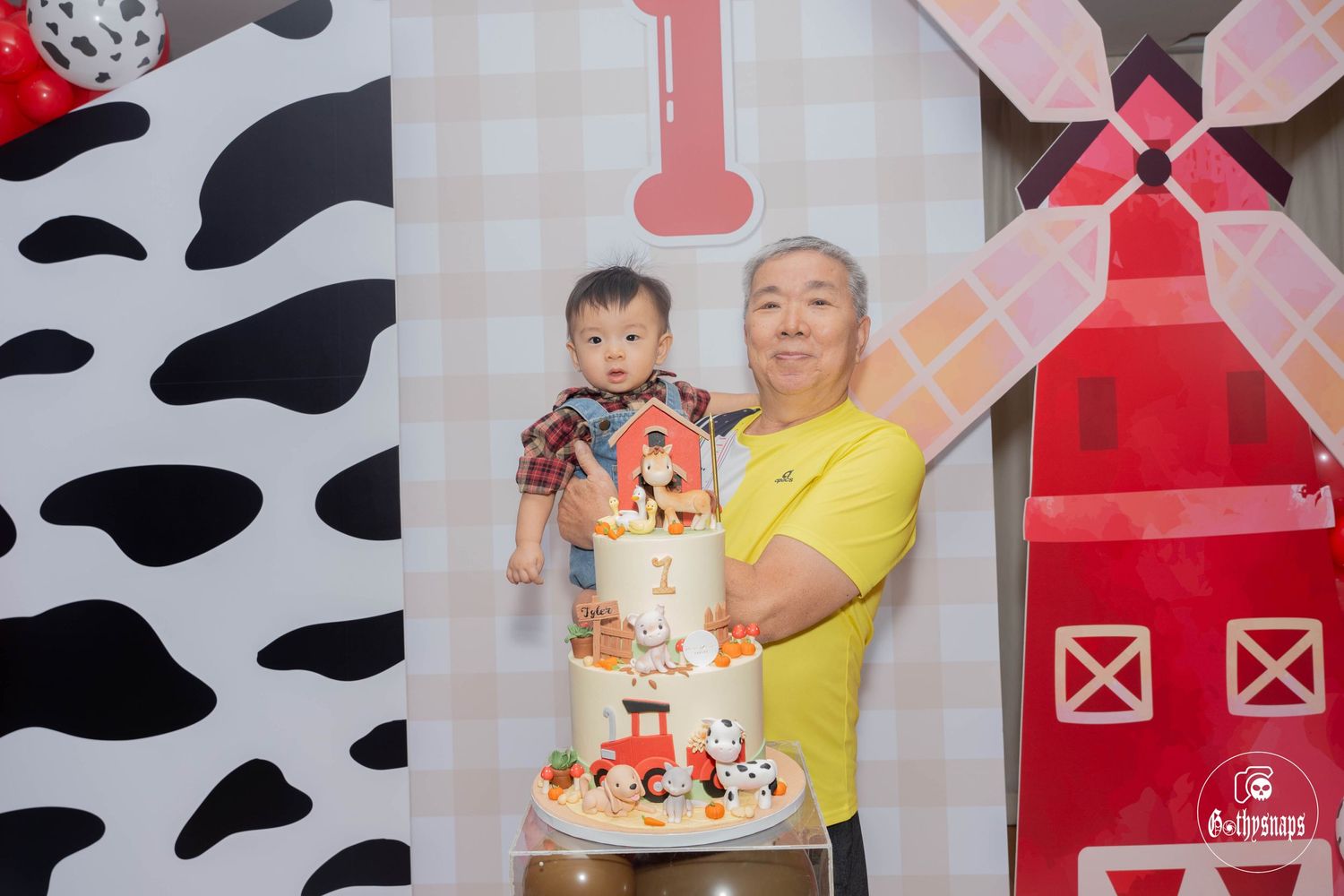 Farm-themed first birthday party with a decorated cake against a backdrop with barn motifs.