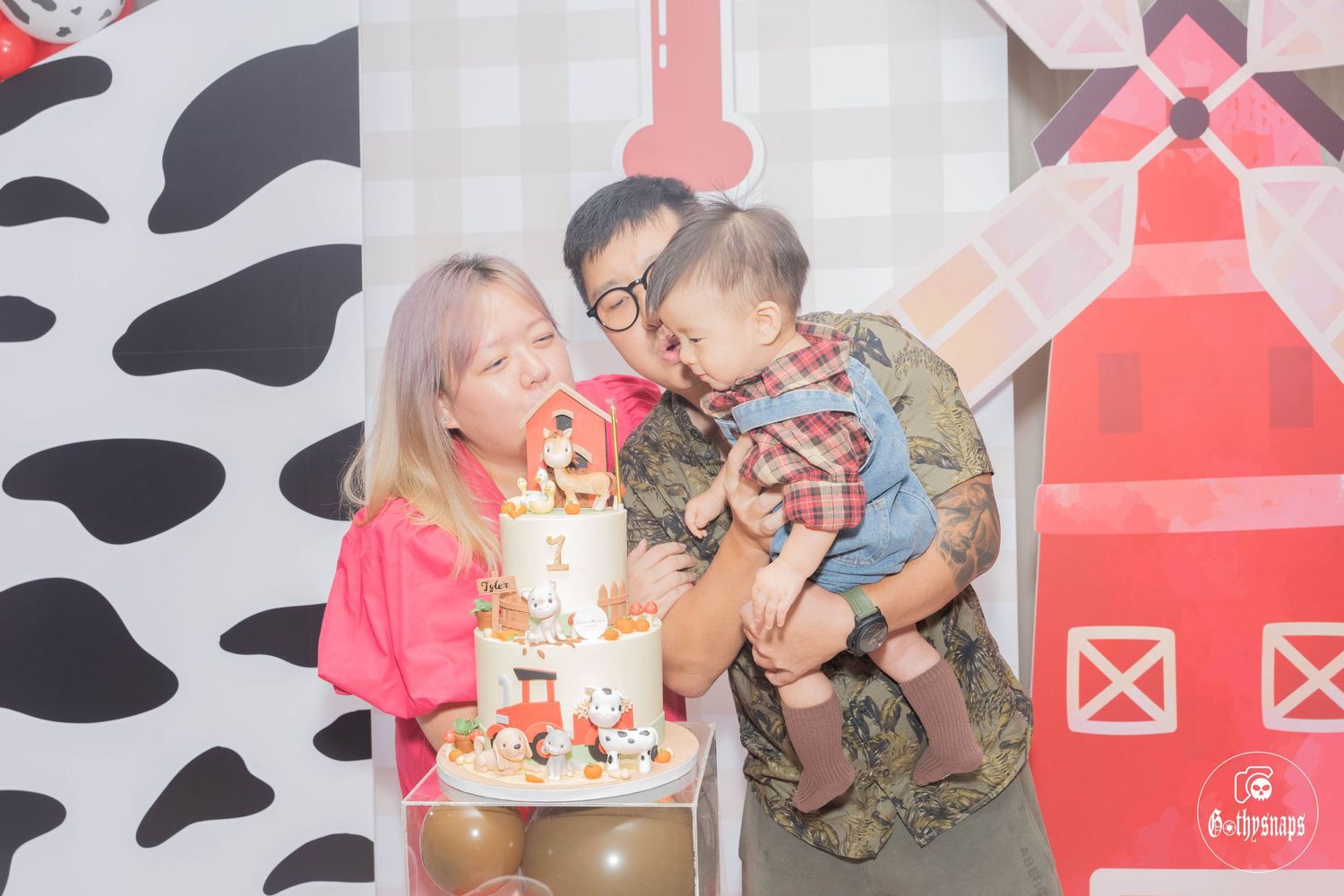 Birthday celebration with farm-themed decorations and a tiered cake against a rustic backdrop.