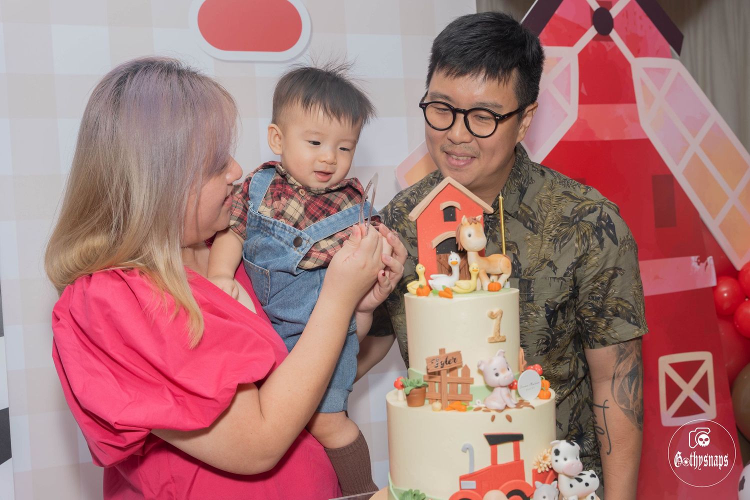 Family celebrating with a farm-themed birthday cake against a decorative barn backdrop.