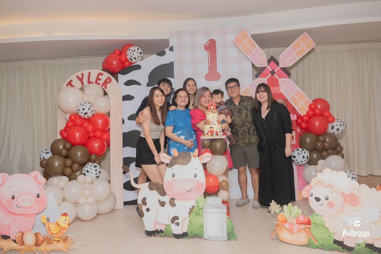Celebration gathering with farm-themed decorations including balloons and barn backdrop.