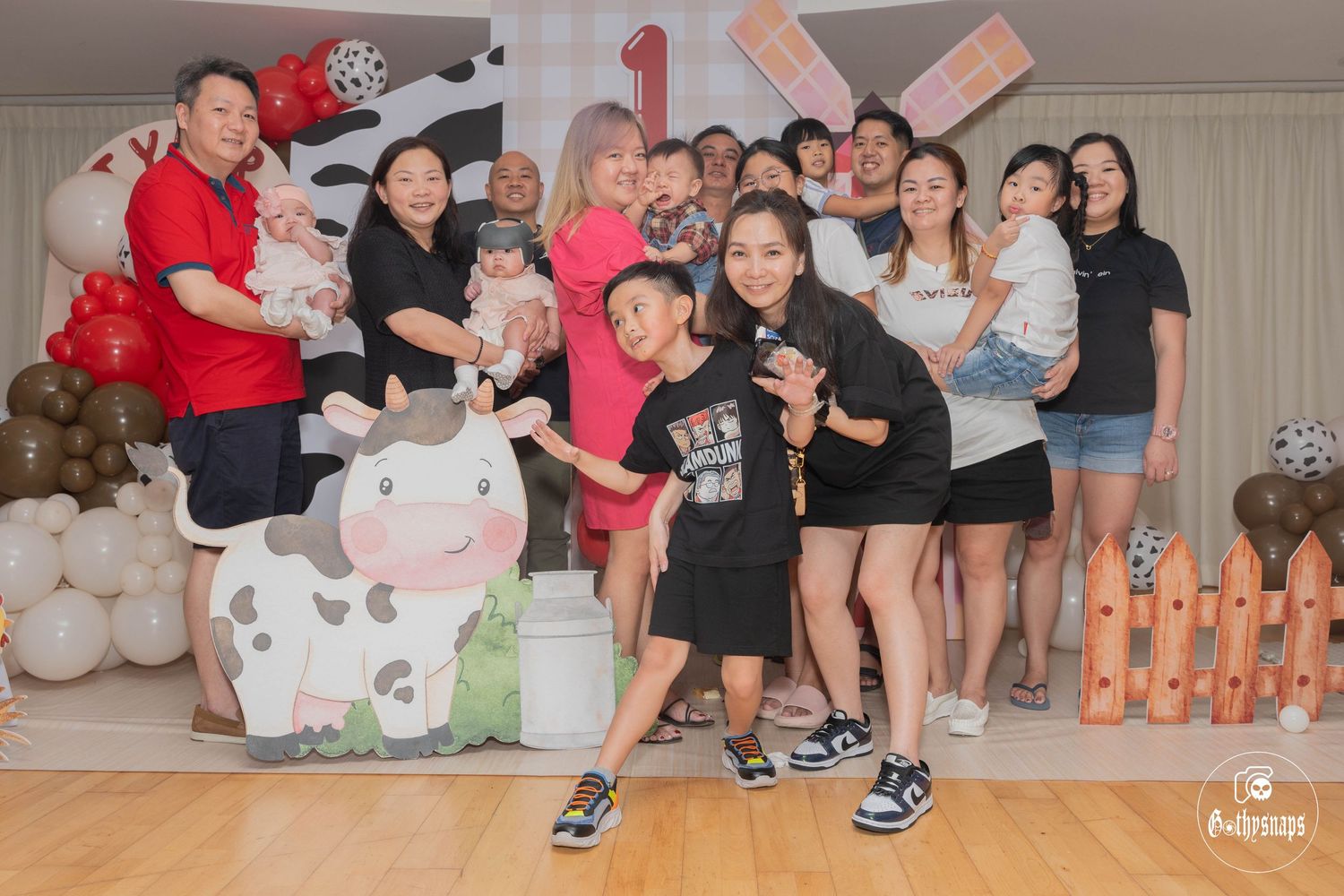 Large group poses together at a farm-themed birthday party with decorative balloon arrangements.