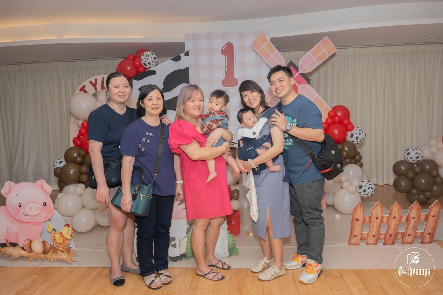 Family photo at a first birthday celebration with farm-themed party decorations.