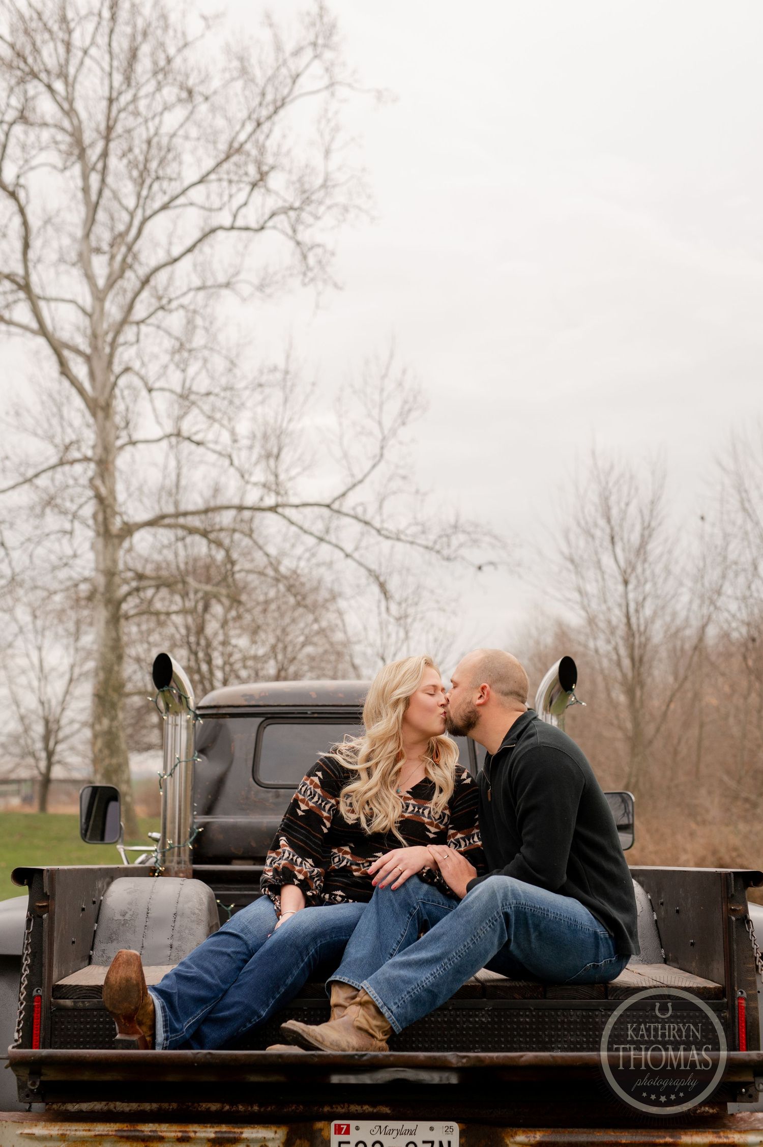 Romantic couple sharing intimate moment in pickup truck bed on cloudy day.