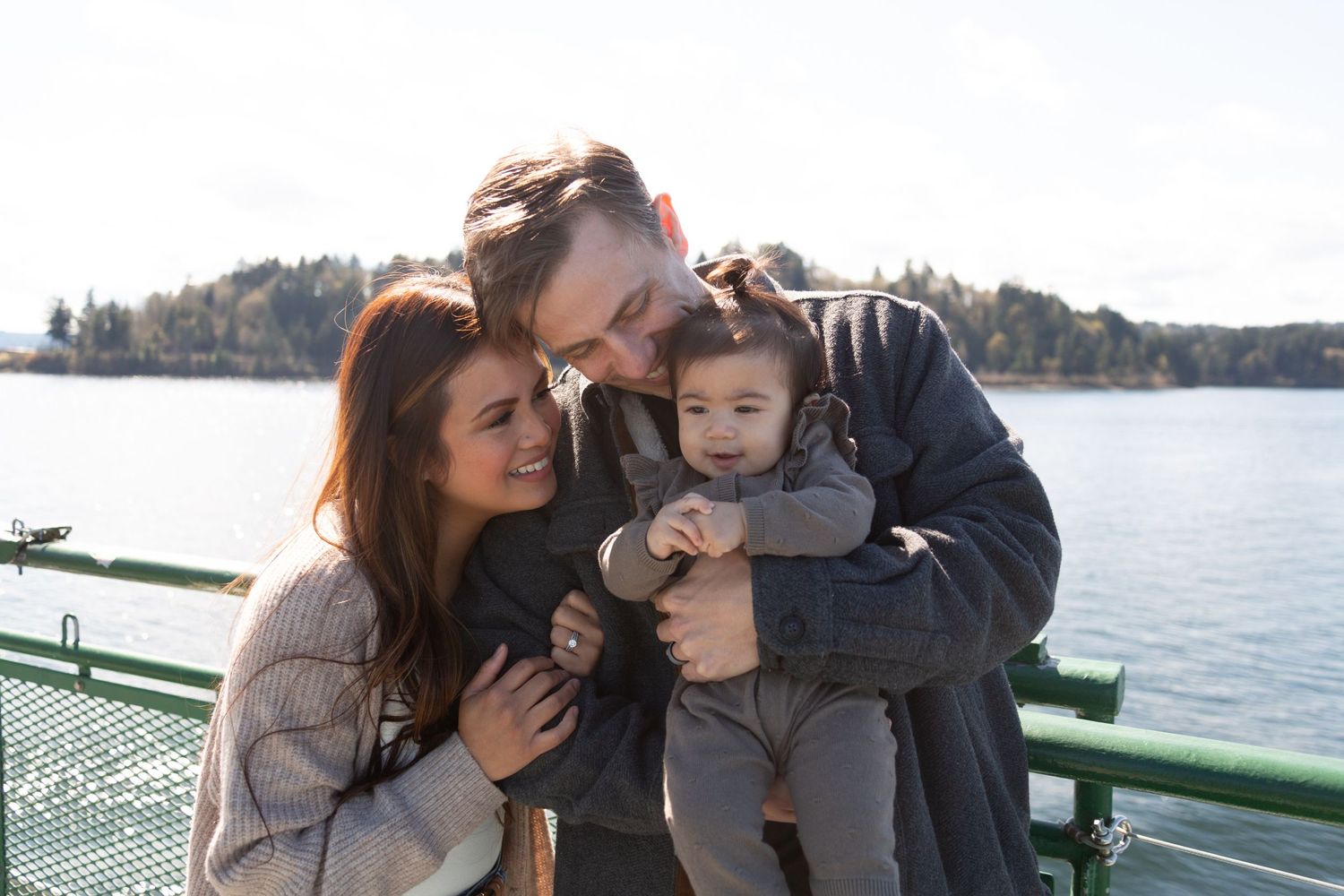 A family shares an intimate moment together on a ferry deck with sparkling water in the background.