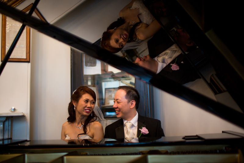 A couple shares an intimate moment while seated at a grand piano.