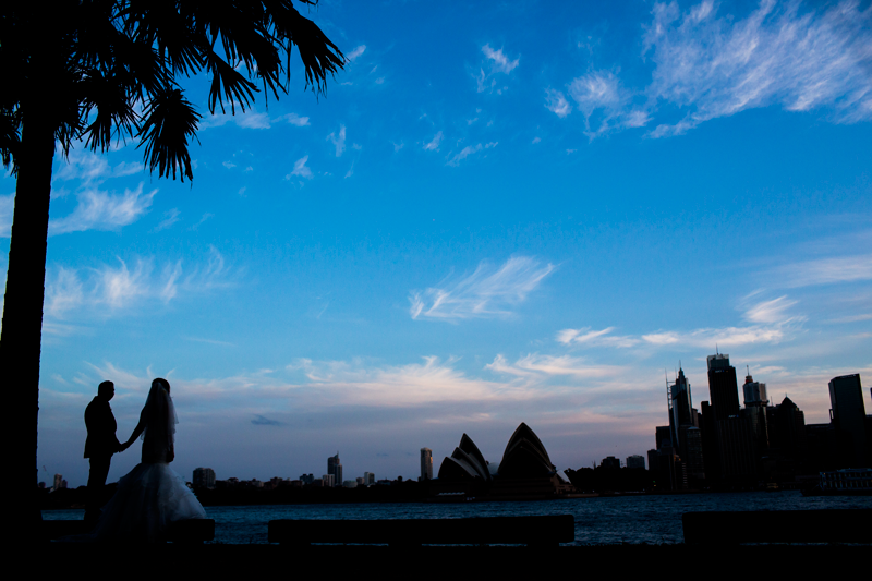 Sydney Opera House and city skyline silhouetted against a blue dusk sky.