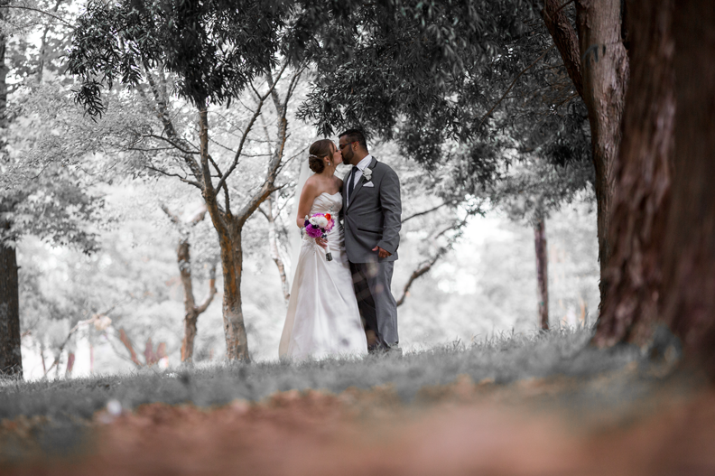 A romantic black and white portrait of a couple among trees on their wedding day.