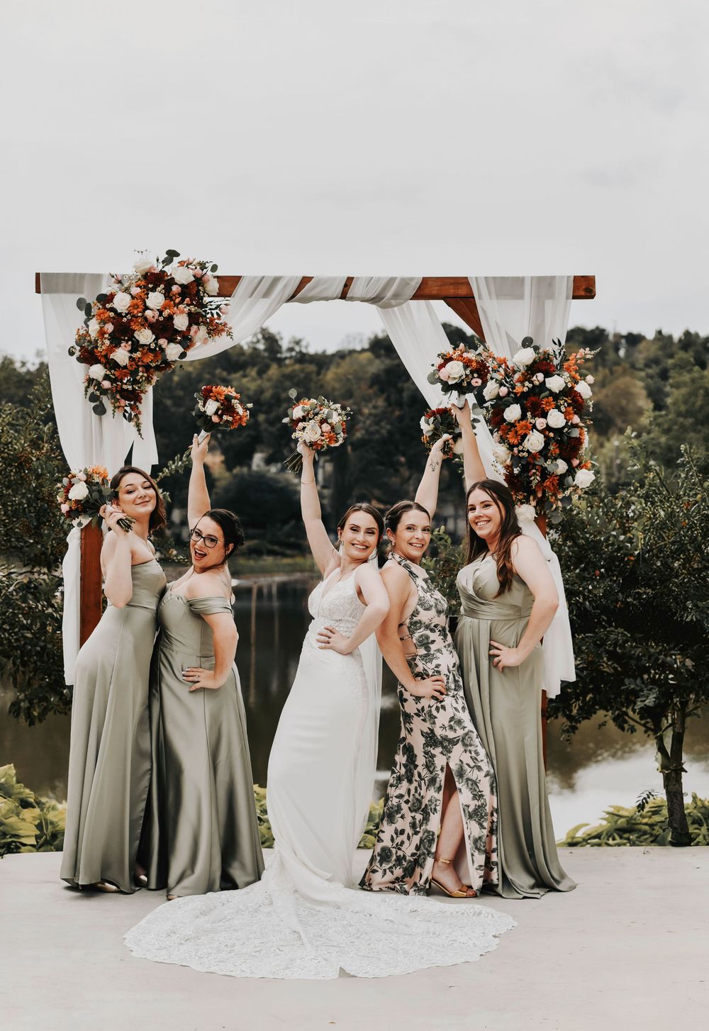 a bride and her happy wedding party celebrate in front of the river at their wedding venue in dallas