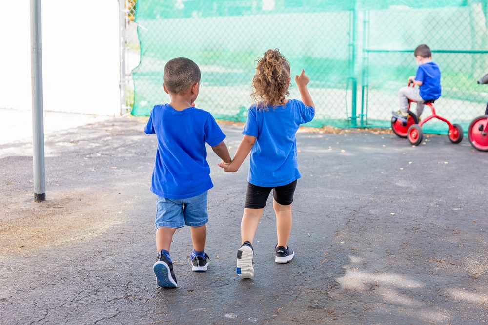 Children walking together on a playground path surrounded by green fencing and outdoor play equipment.
Schools photography.