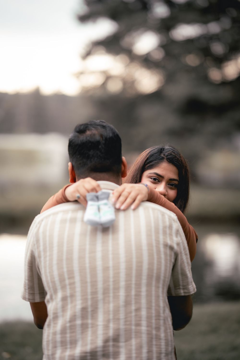 A couple embraces in a romantic sequence of photos showing them hugging against a soft outdoor background.