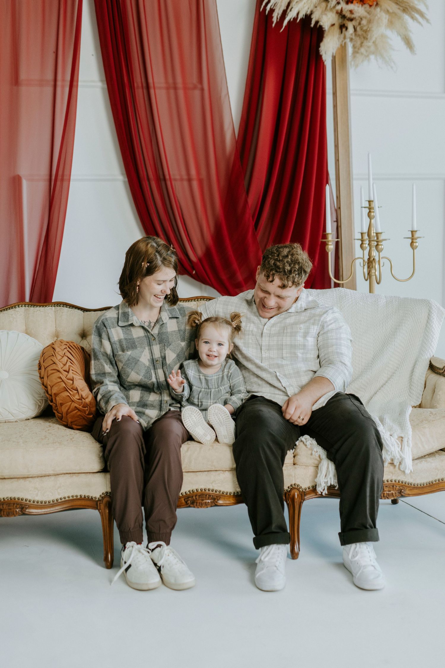 Four sequential photos show feet of people sitting on an elegant cream sofa with red curtains in the background.