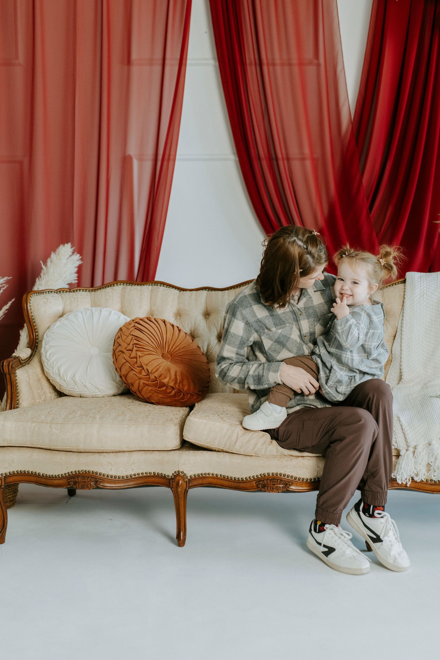A series of images showing someone lying on a cream colored vintage couch with red curtains in the background.