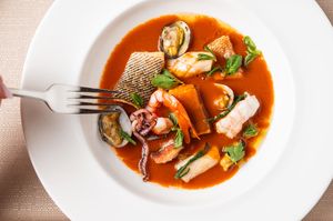 Seafood soup with shellfish and vegetables served in white bowls.