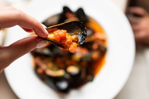 Close up of seafood stew being eaten with a fork.