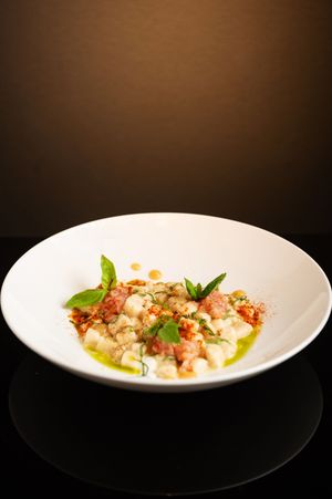 Modern fine dining dish with seafood and garnishes presented on a pristine white plate.