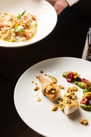 Elegantly plated dish with walnuts and roasted vegetables on a white ceramic plate.