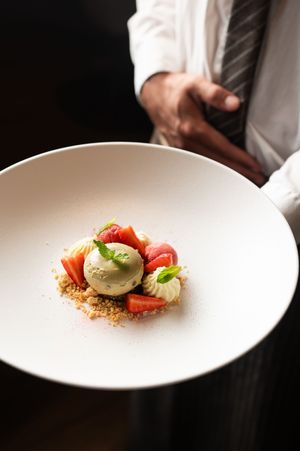 Minimalist plating of fresh ingredients on a stark white plate against a dark background.