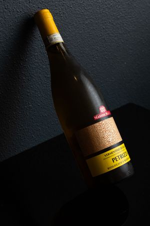Wine bottle with gold label photographed against dark textured background.