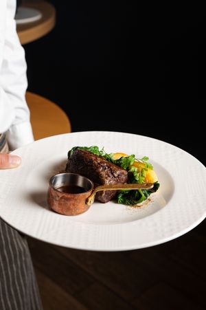Perfectly cooked steak with seasonal vegetables plated on white porcelain.