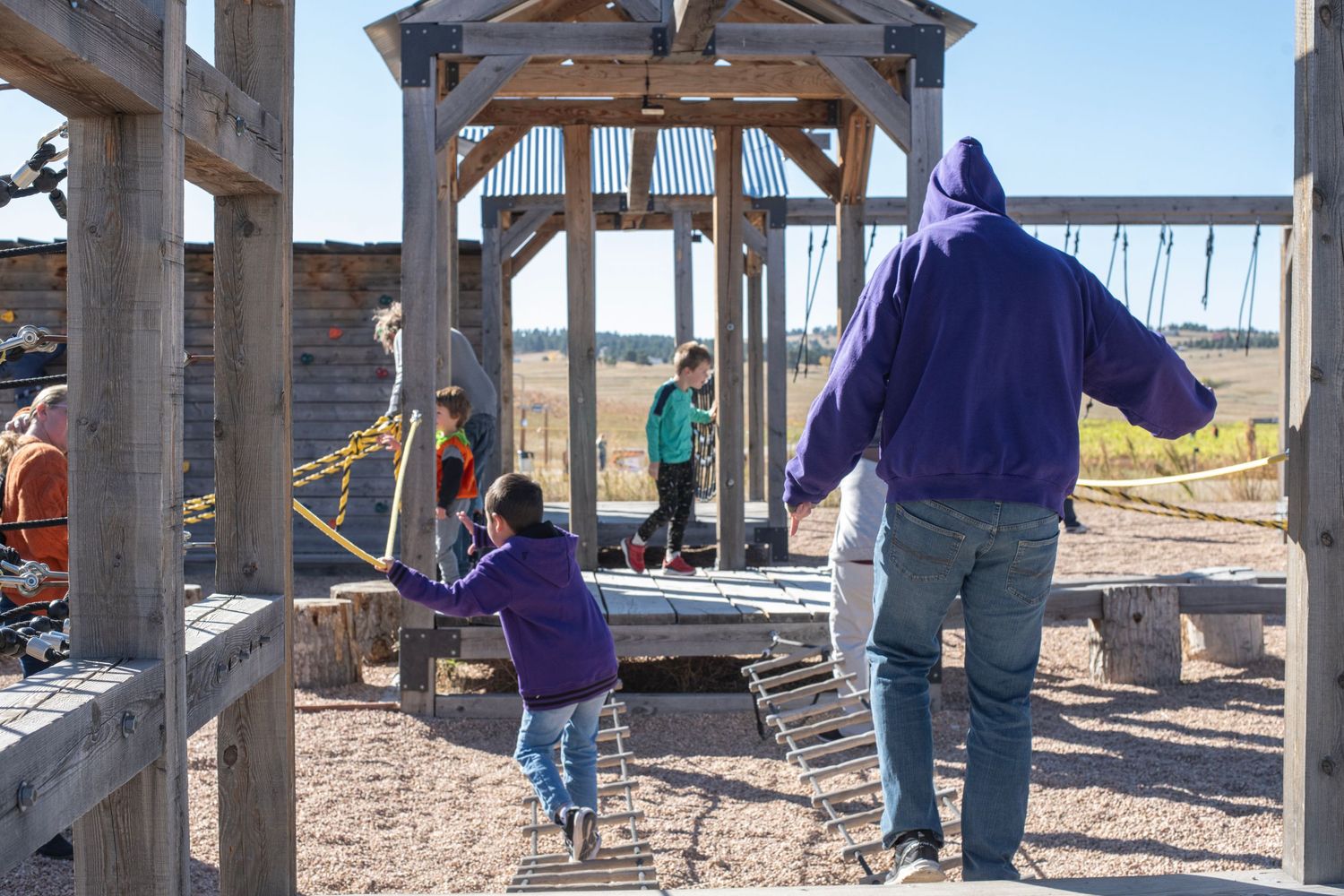 Volunteers work together to construct wooden framing for a community building project in an outdoor setting.