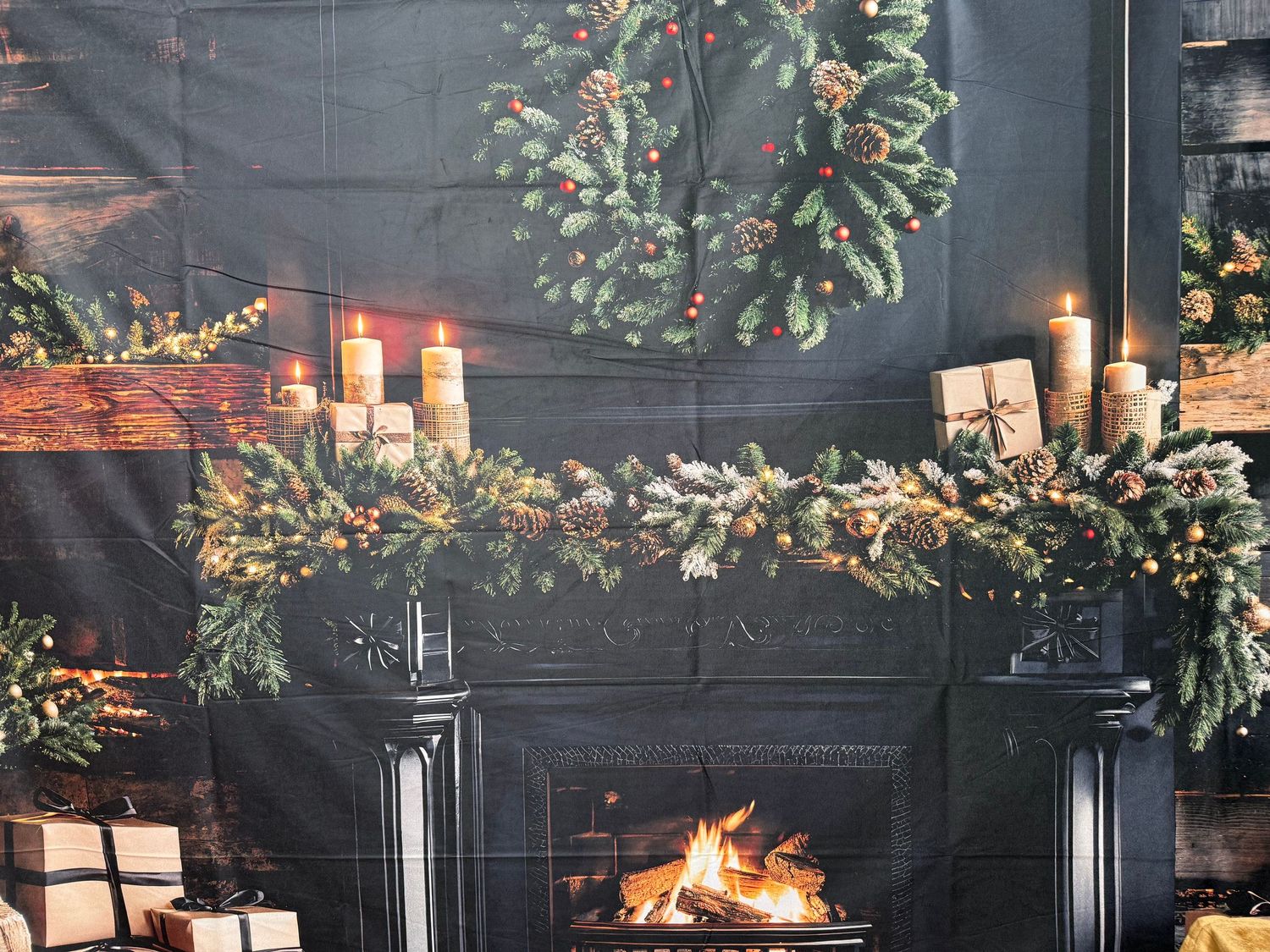 Rustic holiday mantel display with stockings, greenery garland, candles and a glowing fireplace in a cozy living room.