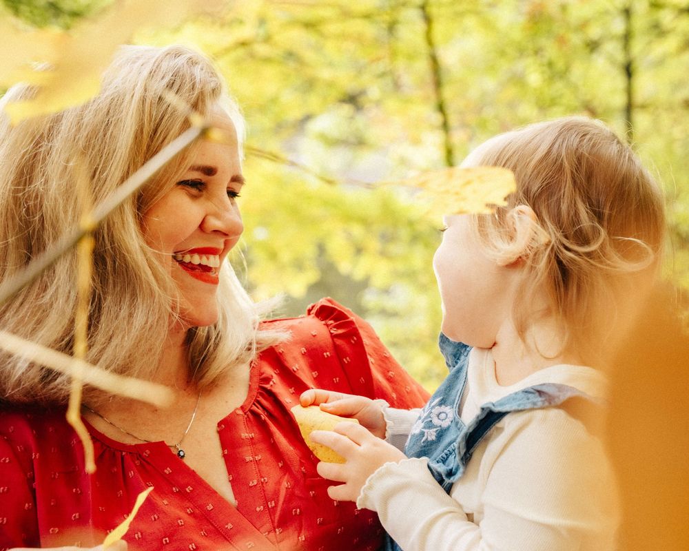 Two women in a sunny outdoor setting share a joyful moment together while wearing red and white outfits.