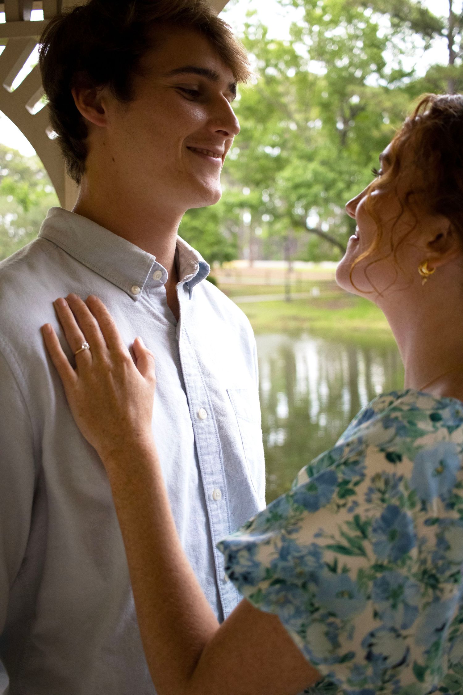 Close-up shot of two people in intimate poses against a lakeside background.