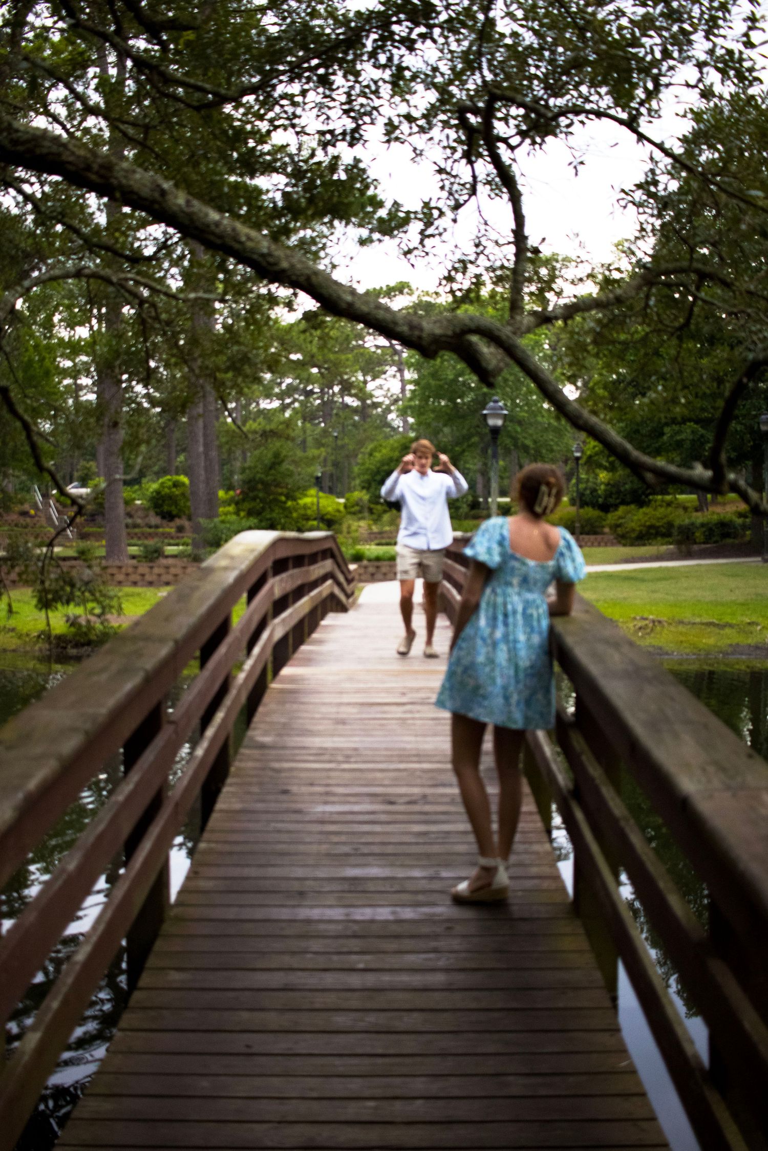 People walking along a wooden boardwalk surrounded by trees and water.