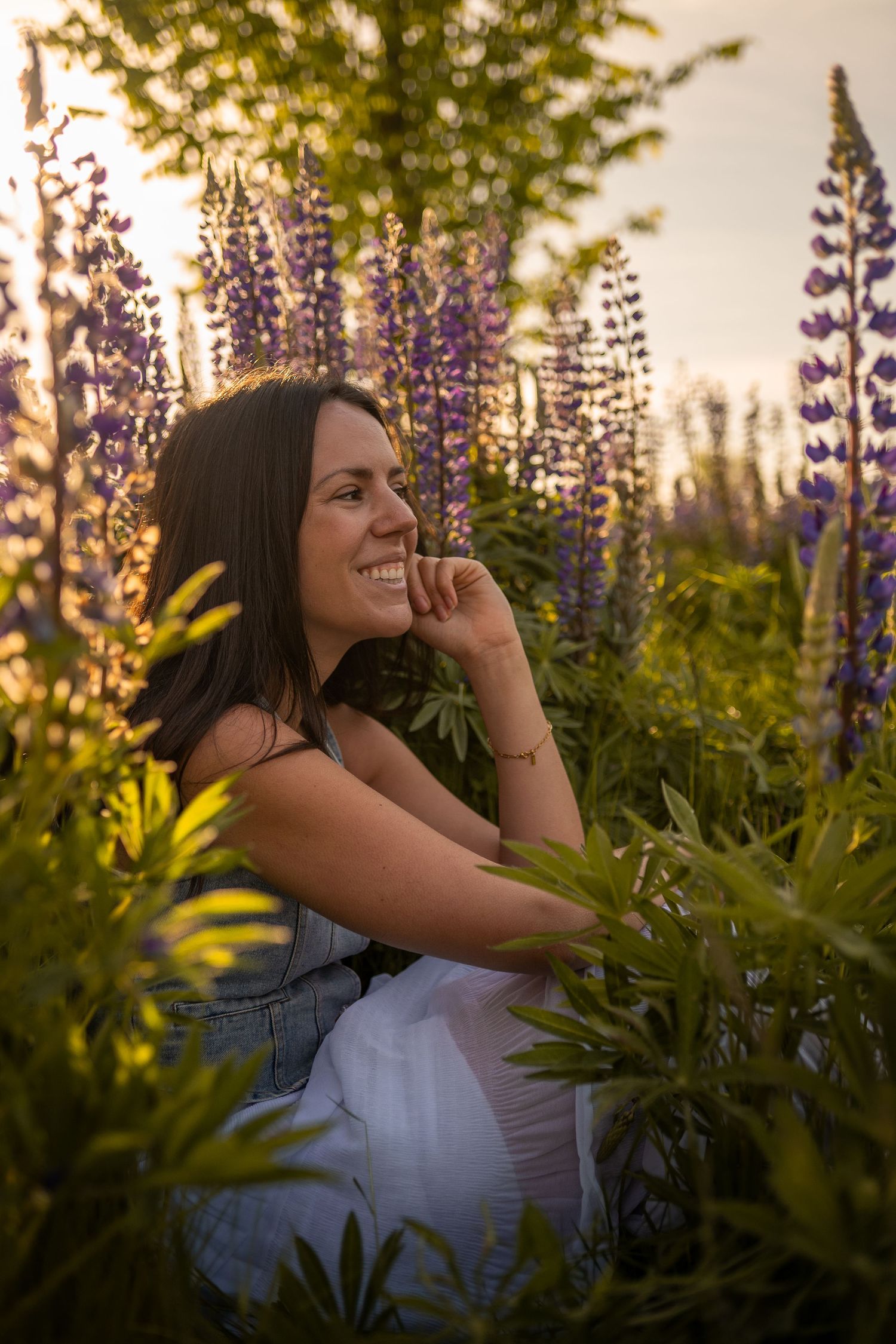 A young woman sits in a field of lupine flowers on a sunny spring day near Puyallup Washington.