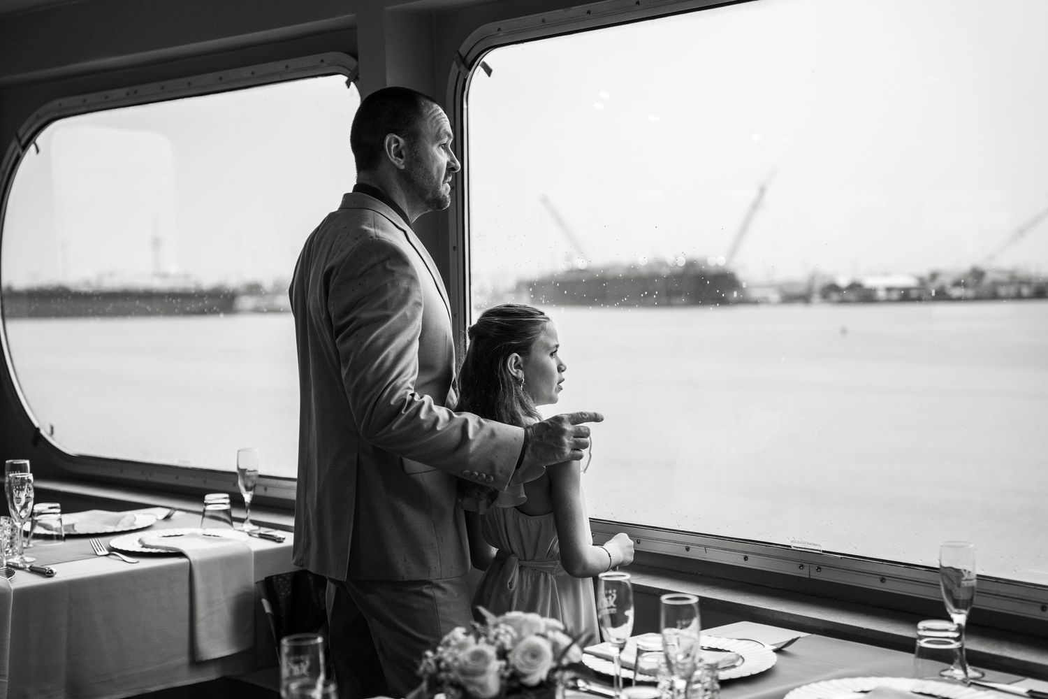 Black and white photo of a wedding ceremony with guests raising glasses in celebration at a reception. Micro wedding on Yacht StarShip in Ta