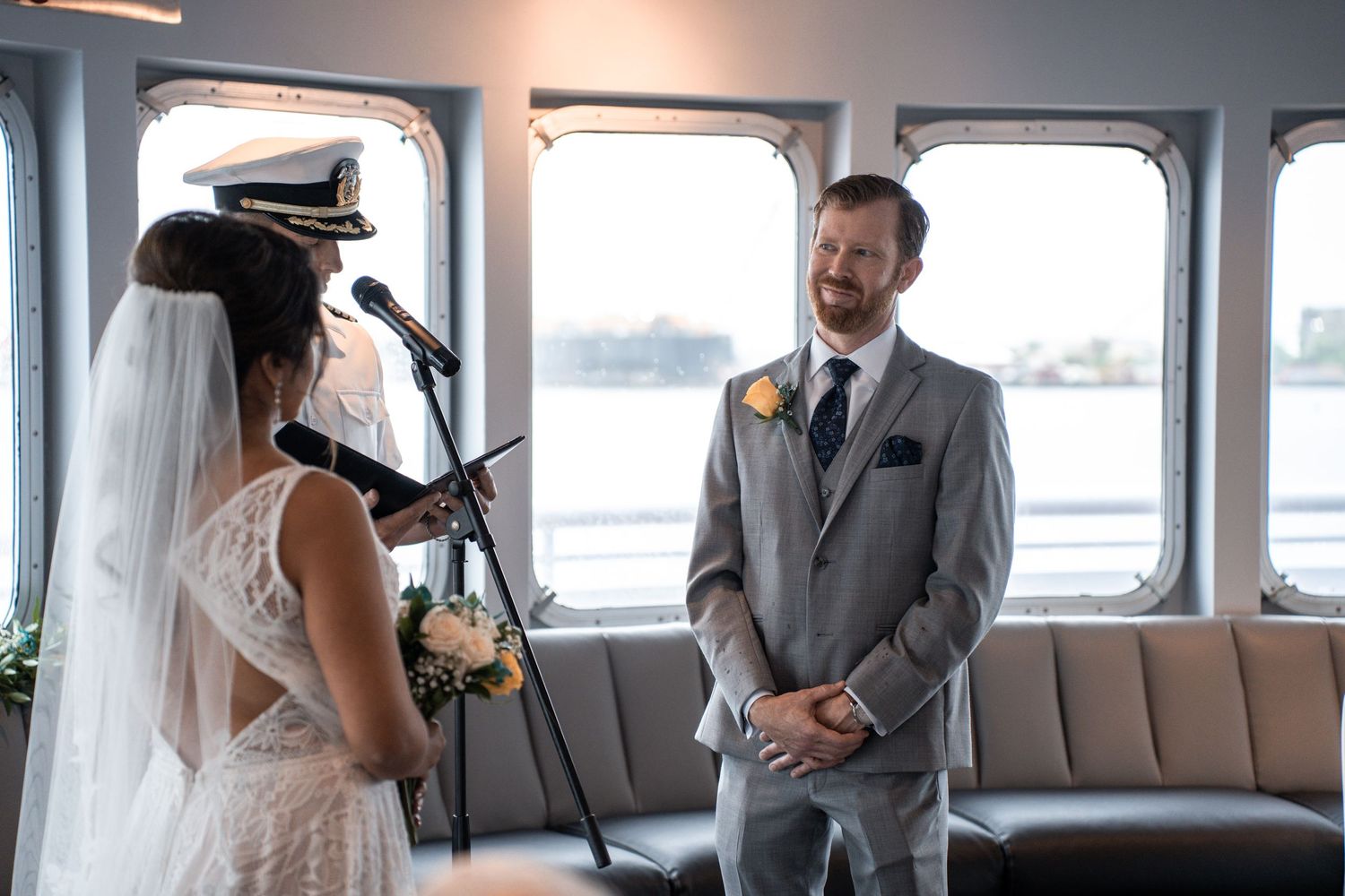 Wedding party gathered in formal attire aboard a yacht with large windows. Micro wedding on Yacht StarShip in Tampa